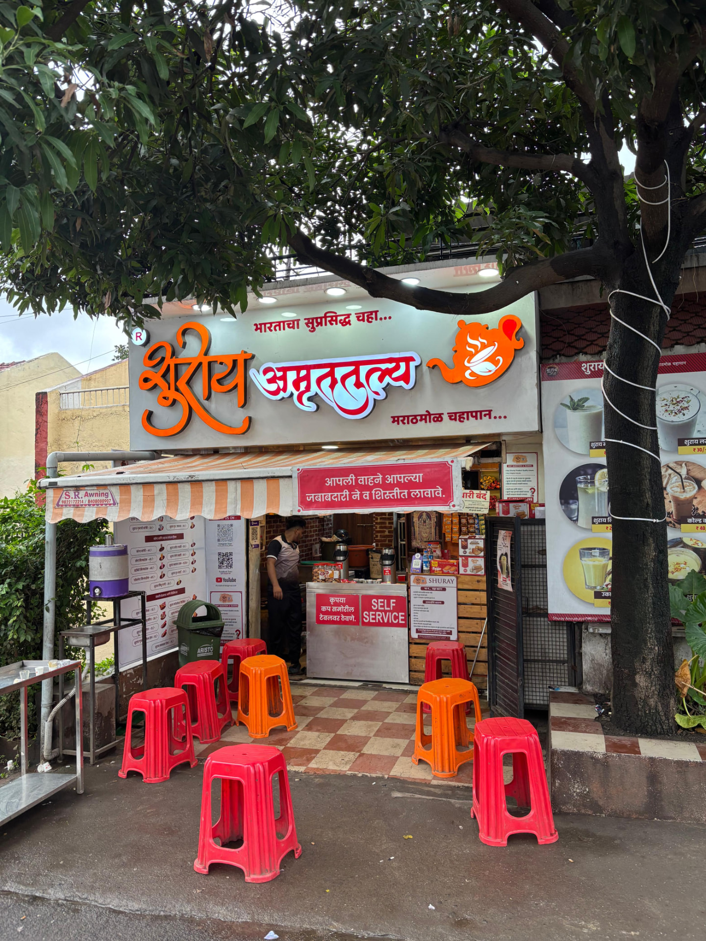 Shuray Amruttulya main outlet with striped awning and outdoor stool seating