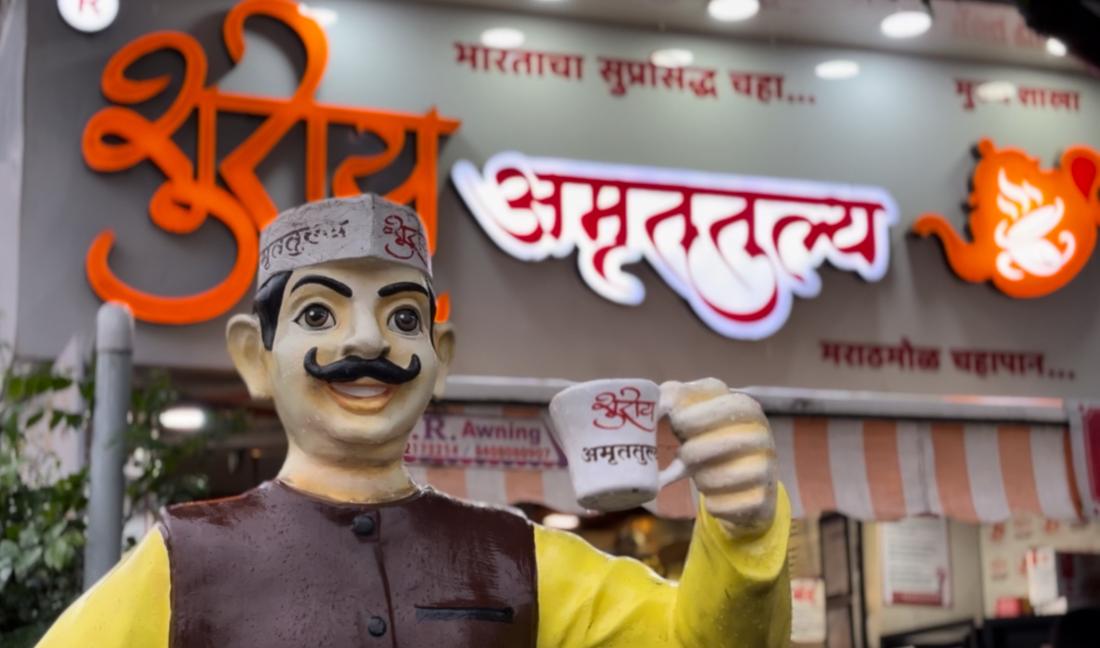 Shuray Amruttulya mascot statue holding a branded tea cup outside an outlet